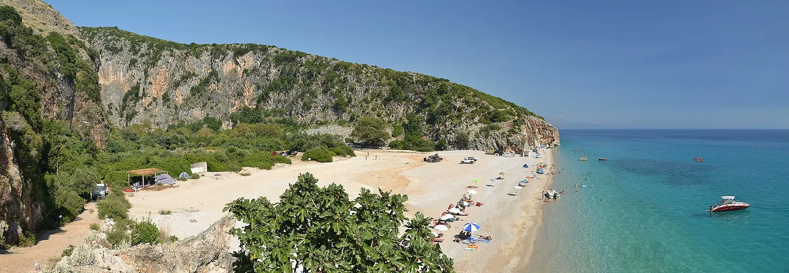 The pebble beach and turquoise water of Gjipe cove framed by cliffs on the Albanian Riviera
