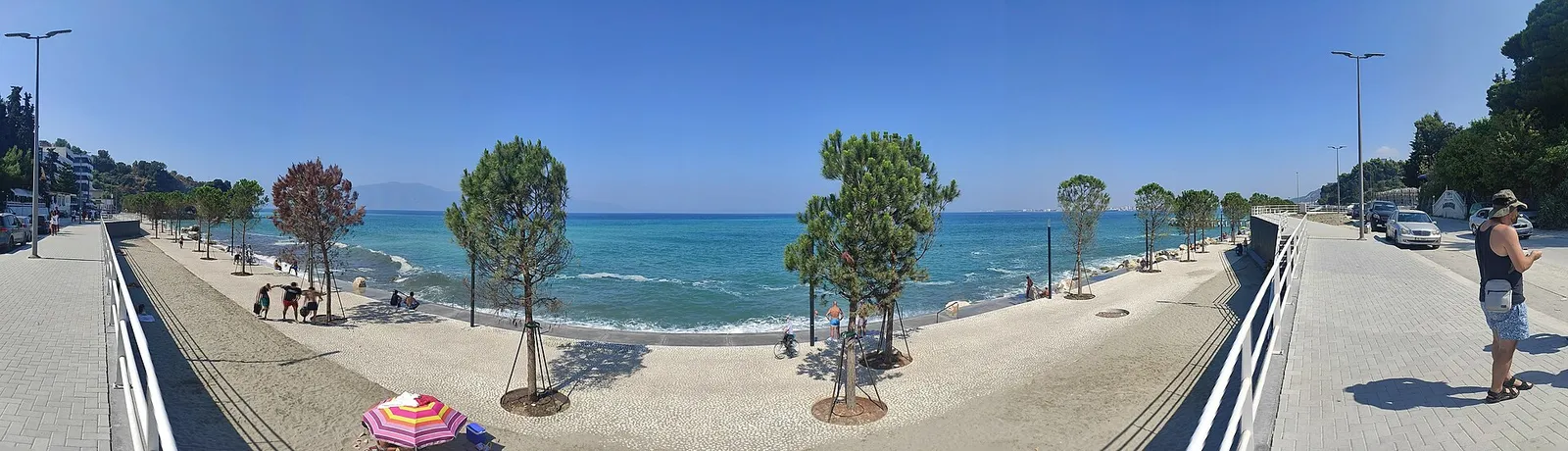 הטיילת של ולורה באלבניה מול הים עם עצים ומדרכה רחבה