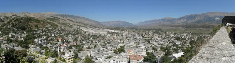 A town of white houses on a slope facing a mountain ridge