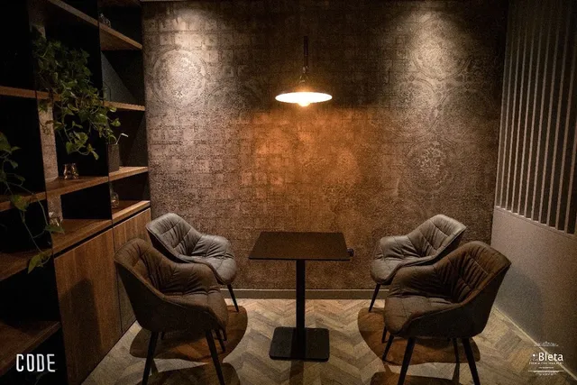 An intimate seating corner with four soft armchairs around a table under a hanging lamp