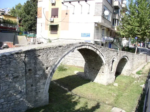 An old stone bridge with two arches between city apartment buildings