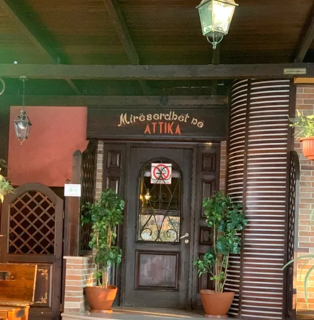 A dark wooden entrance with a carved sign, hanging lanterns and pots on both sides of the door