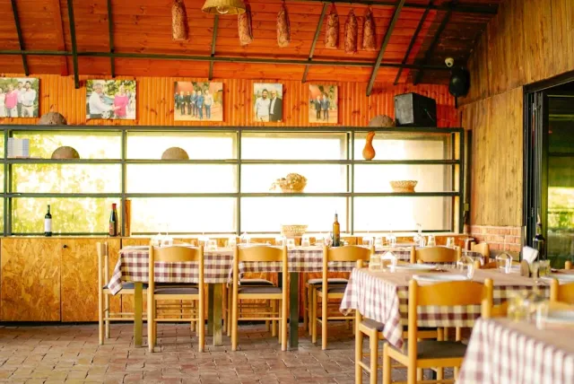 A rustic hall with sausages hanging from the ceiling, red checked cloths and photographs on the wall