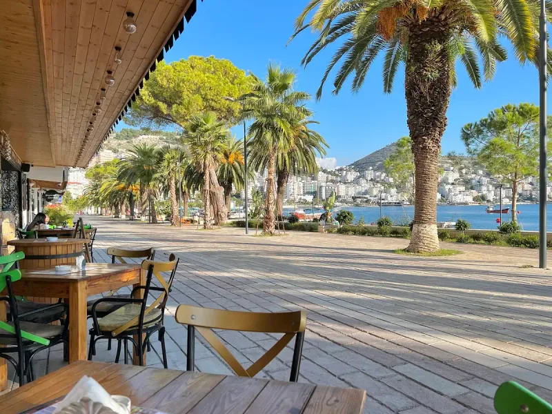 A restaurant terrace with palms facing the bay