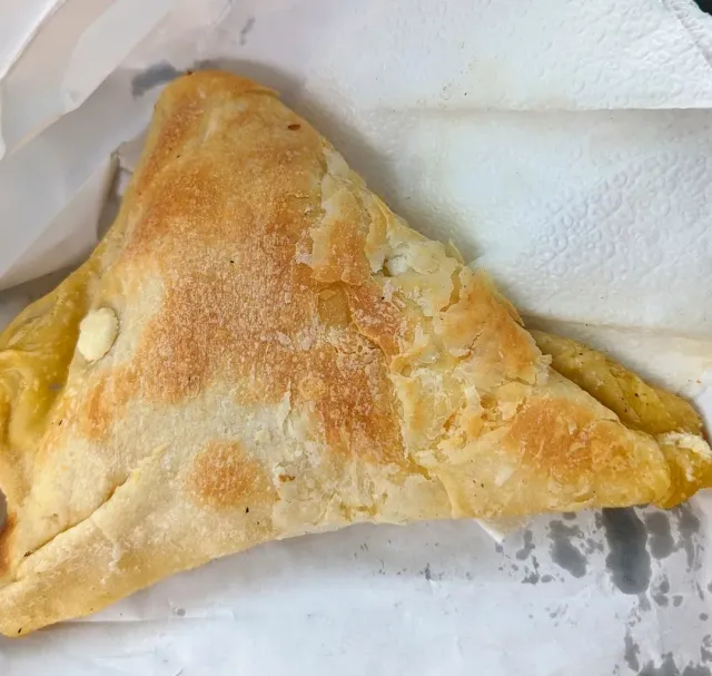 A baked shiny puff pastry triangle resting on a white paper napkin