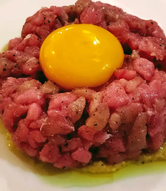 Chopped raw meat tartare with a whole yolk in the middle and olive oil around
