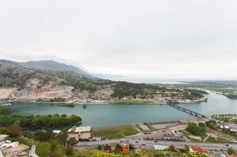 A wide lake with a bridge and hills behind