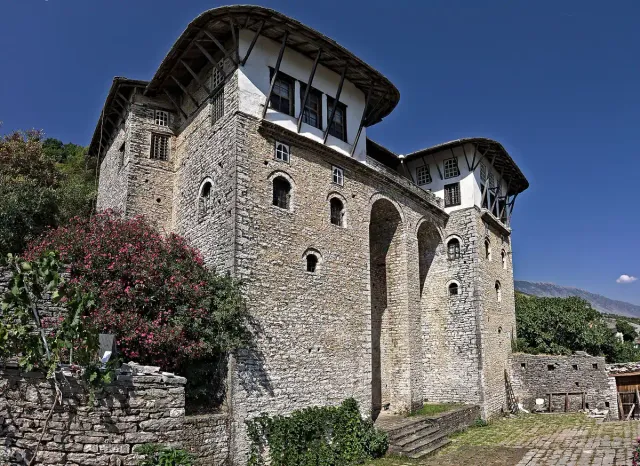 A three storey Ottoman stone house with arched windows and a flowering tree beside it