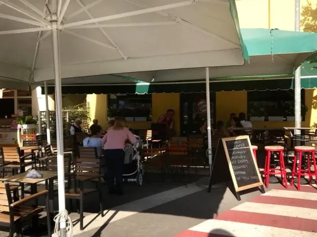 Outdoor seating with white parasols, red stools and a chalk menu board