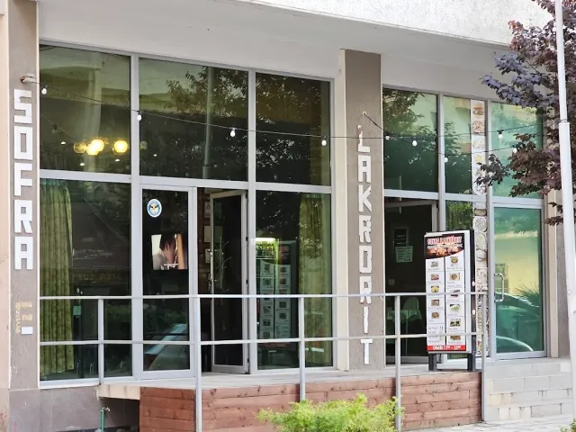 A building front with large windows, vertical signs, hanging bulbs and a menu board at the entrance