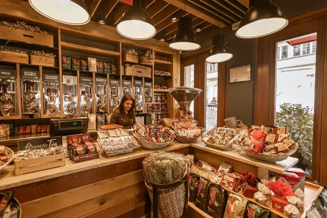 A warm wooden space with coffee bean dispensers, baskets of products and lamps hanging above the counter