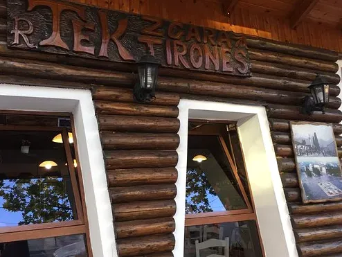 A log built front with a carved sign, two windows and lanterns on both sides