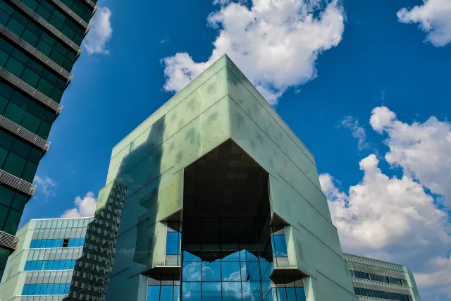 The modern glass and metal facade of a shopping centre against a blue sky