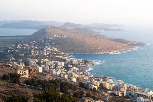 A view from above of a coastal town spreading along a headland facing the sea