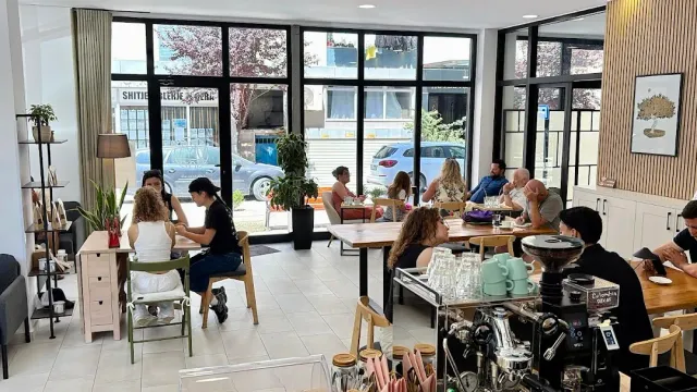 A bright space with large windows, people seated around tables and a roasting machine on the counter