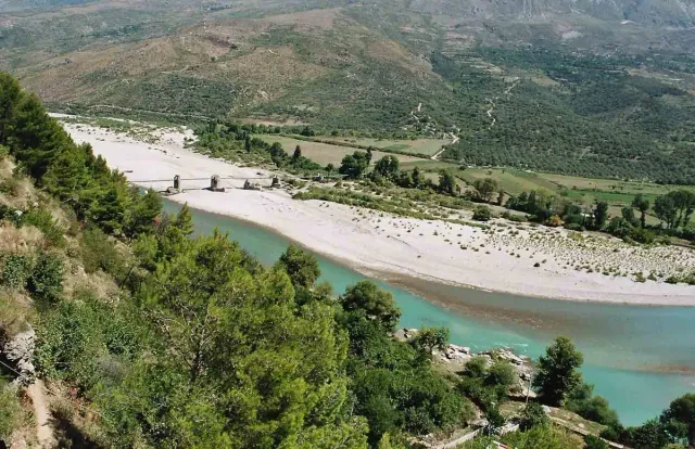 A turquoise river winding between wide gravel banks and green hills