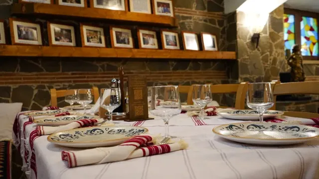 A table set with decorated plates and striped napkins, against a stone wall with framed photographs