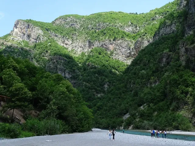 A clear river between steep green mountain slopes on both sides