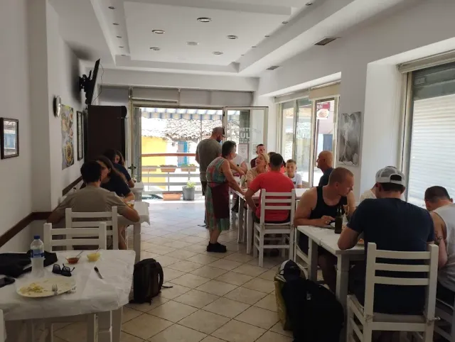 A bright room with white plastic chairs and diners around tables, and a door open to the street