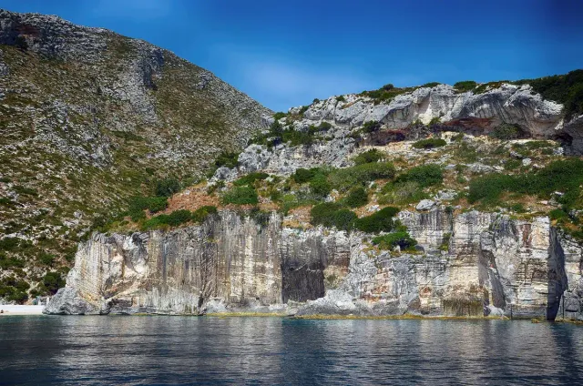 White rock cliffs dropping into deep blue water in a secluded bay