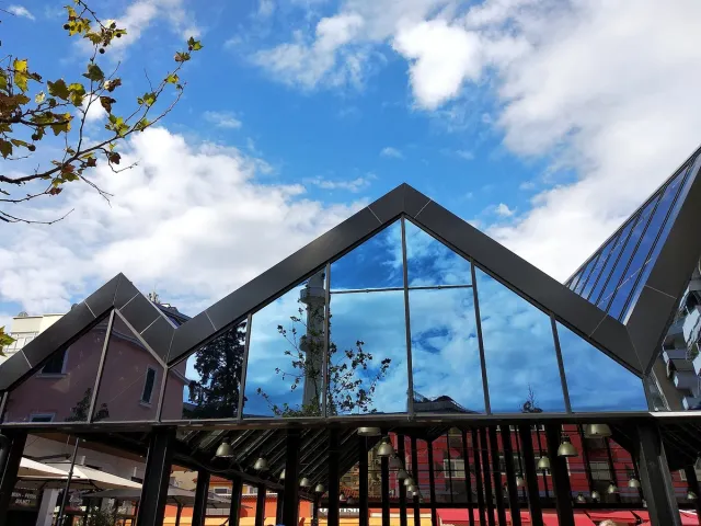 The sloping glass roofs of a city market pavilion against a cloudy sky
