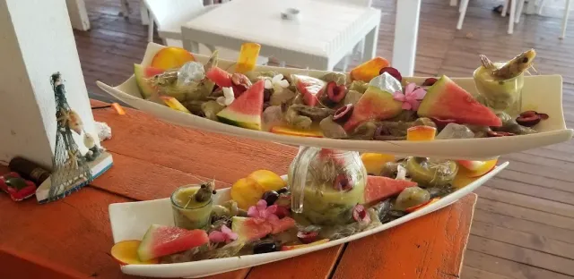 Two elongated plates with seafood, watermelon triangles, olives and flowers on an orange table