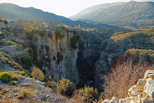 A deep canyon with vertical rock walls cutting through an open plateau