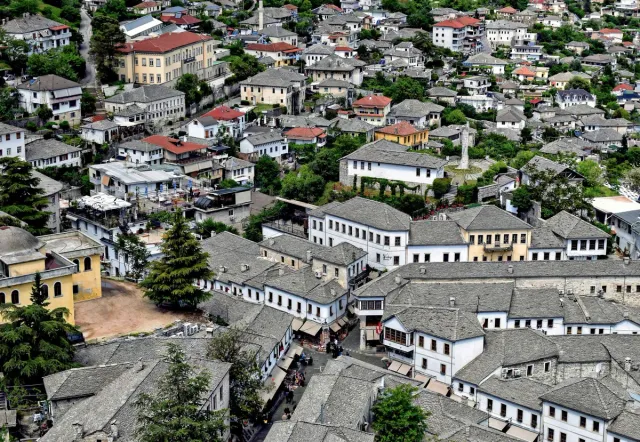 Grey stone roofs of dense white houses on a slope, with a small street between them