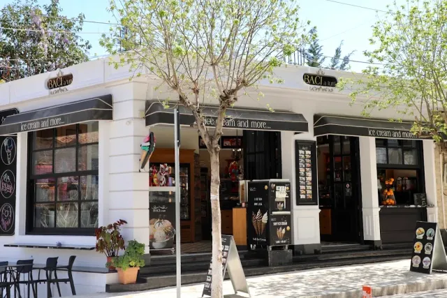 A black and white corner frontage with awnings, display windows and a young tree in front