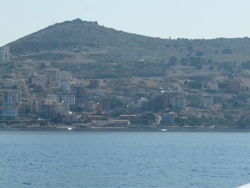 A hill with a port town at its foot across the water