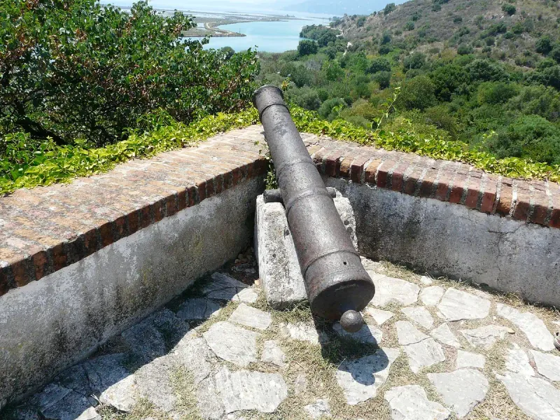 An old cannon on a fortress wall above a water channel