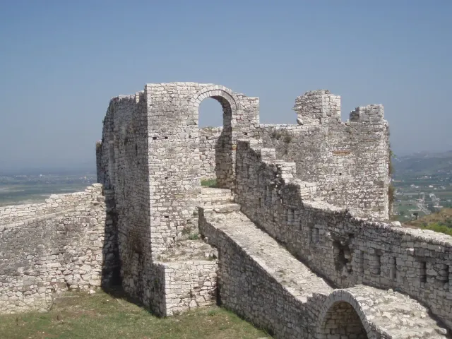 Stone fortress walls with a watchtower on a ridge above an open valley