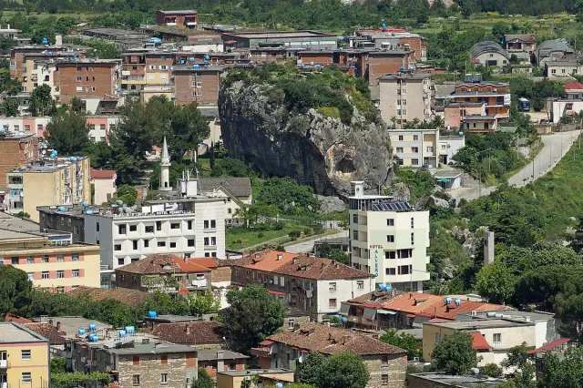 A giant grey rock standing in the middle of a town of tiled roofs and apartment blocks
