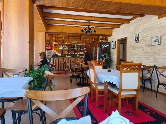 A hall with wooden beams, a bottle bar, tables in white cloths and a long red rug