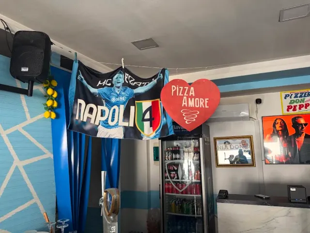 A light blue wall with a hanging football flag, a red heart sign and a drinks fridge by the counter