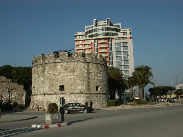 A low round stone tower from the remains of a city wall beside an urban road