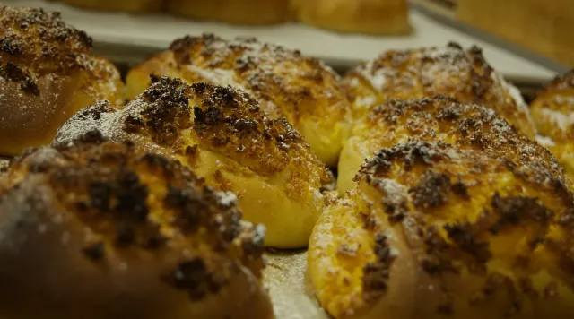 Golden sweet buns close up, with dark crumble and icing sugar
