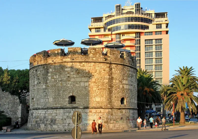 A round stone tower with palms around it