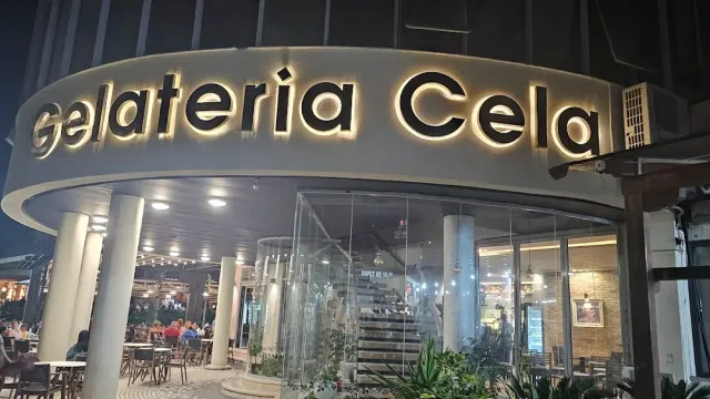 A large illuminated sign above a rounded entrance with columns, and outdoor seating at night