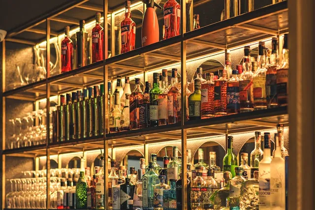 Lit glass shelves packed with liquor bottles and wine glasses