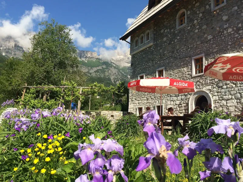 A stone mountain house with irises in front