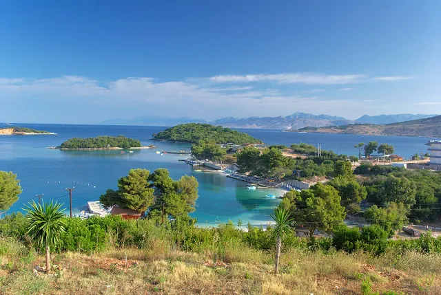 Small green islets in a turquoise bay with white sand coves and a mountain ridge behind