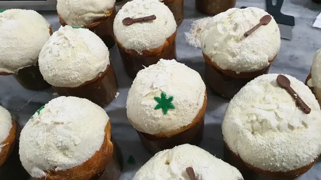 Individual yeast cakes covered in white cream and coconut flakes, decorated with chocolate spoons