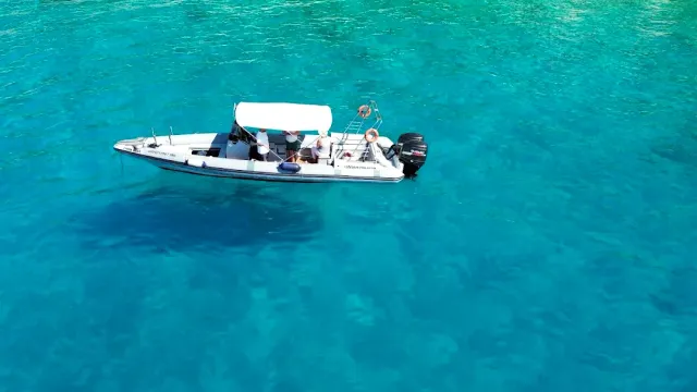 A speedboat with a white canopy on clear turquoise water, seen from above