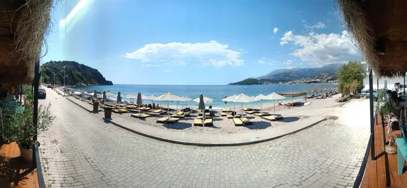 A pebble beach with parasols facing clear water