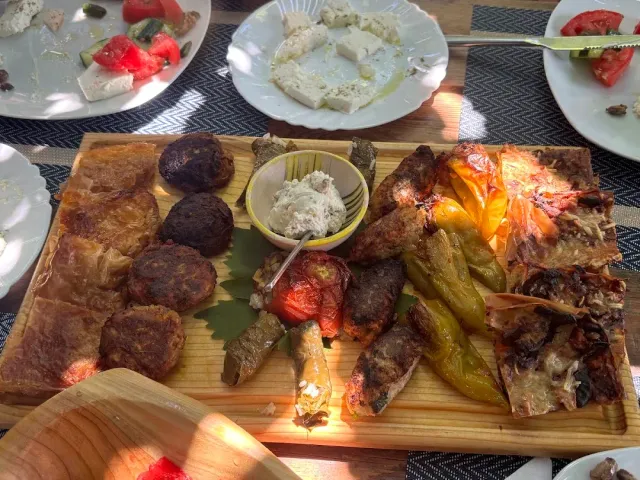 A wooden board loaded with patties, stuffed vegetables, roasted peppers and slices of pastry