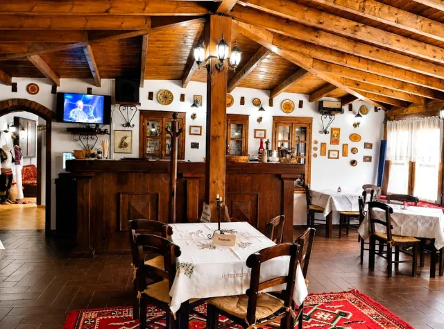 A hall with wooden beams, decorated plates on the walls, a wooden bar and colorful rugs