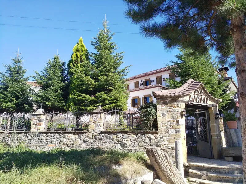 A traditional stone house behind a gate and railing
