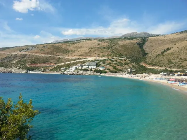 A bay with bright turquoise water and a pebble beach at the foot of a dry slope
