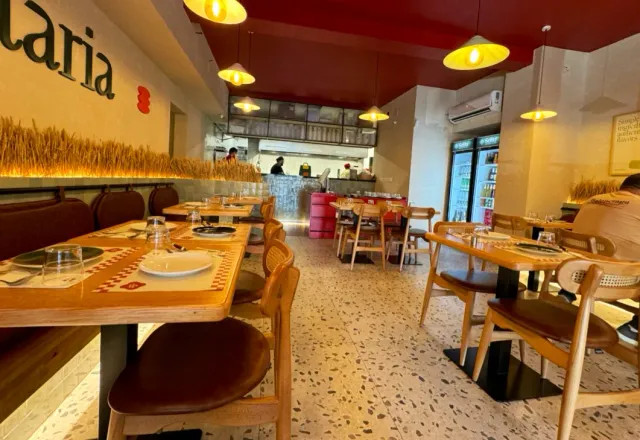 A room with a red ceiling, yellow lamps, wooden tables and an open kitchen counter behind